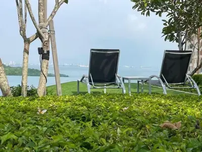 two chairs sitting in the grass near the water at Breezy Urban 6pax SeaView InfinityPool Georgetown in George Town