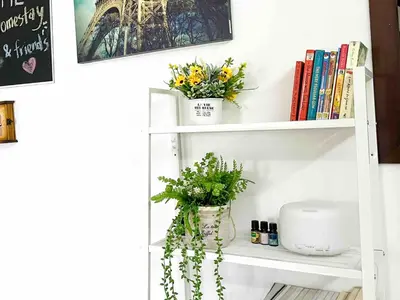a white shelf with flowers and books on it at \u60a6\u5ba2YK Homestay 5mins to IconCity in Bukit Mertajam