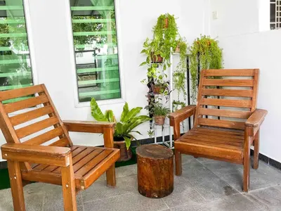 two wooden chairs sitting on a porch with plants at \u60a6\u5ba2YK Homestay 5mins to IconCity in Bukit Mertajam