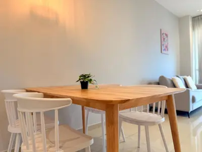 a wooden table in a living room with white chairs at Iconic Regency Seaview Homestay with Rooftop Pool in Bayan Lepas