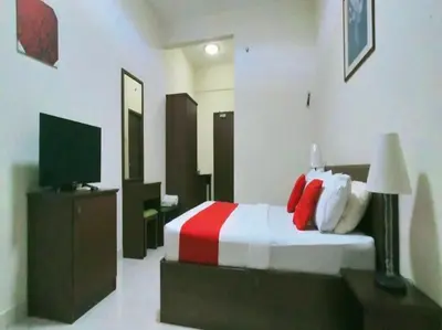 a bedroom with a bed with red pillows and a television at Suria Escape Bukit Merah in Simpang Ampat Semanggol