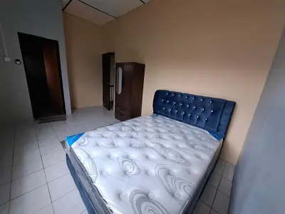 a bedroom with a bed in a room with a refrigerator at Family Homestay Bidor in Gua Sai