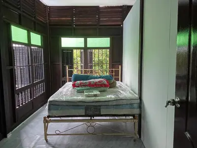 a bedroom with a bed in a room with windows at Teratak Taha in Kepala Batas
