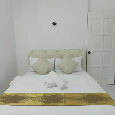 a white bed with white pillows and a gold and white blanket at Olive home in Ipoh