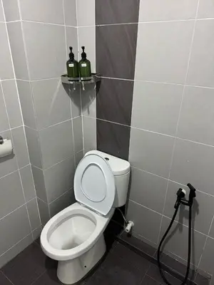 a bathroom with a toilet and two bottles on a shelf at Modern & Cozy Home Stay in Kampar