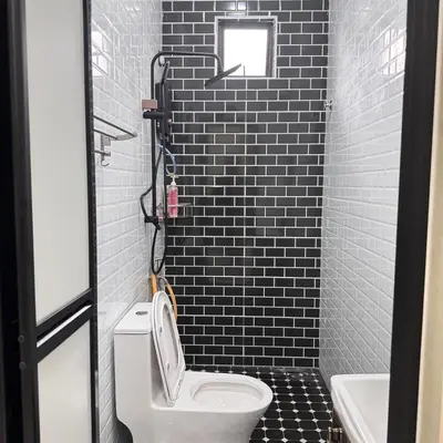 a bathroom with a white toilet and black tiles at Homestay D'Ammar Private Pool in Gua Sai