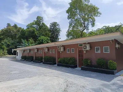 a large red building with bushes and trees at Ulu River Lodge, Riverbug Perak in Gopeng