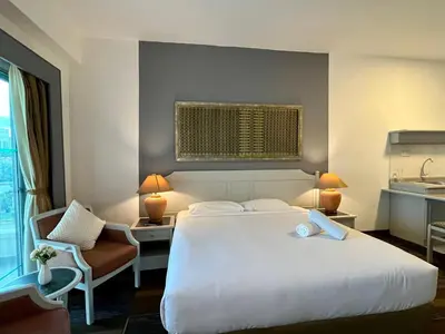 a hotel room with a large white bed and a chair at Maisie Rainbow Penang in Tanjung Bungah