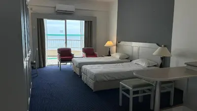 a hotel room with two beds and a table and chairs at Maisie Rainbow Penang in Tanjung Bungah