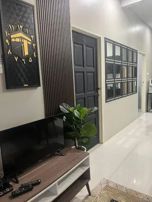a living room with a television and a clock on the wall at AISY Homestay MERAPOH in Pulai