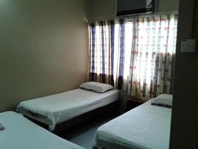 a room with two beds and a window with curtains at HotelMalaya in Taiping