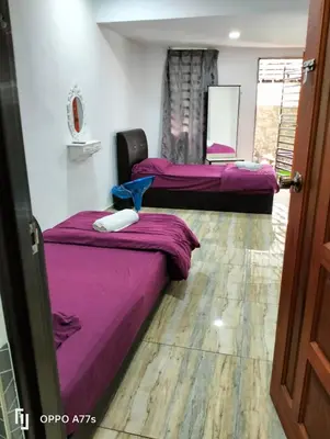 three beds in a room with purple sheets at RJ design homestay in Kampong Batu Lapan