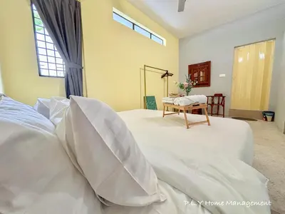 a bedroom with a bed with white sheets and a table at Bercham Landed CornerLot 6BR with Karaoke Set & BBQ in Ipoh