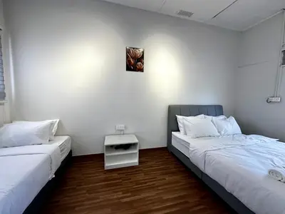 two beds in a room with white walls and wooden floors at Molek Vacation Home in Gelugor