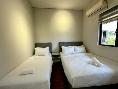 two beds in a small room with white sheets at Molek Vacation Home in Gelugor