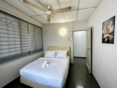 a small room with a bed and a ceiling fan at Molek Vacation Home in Gelugor
