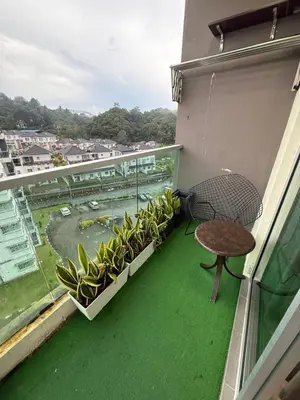 a balcony with a table and some plants on it at AYAAN Flora Quintet Apartment & Fifa Home 4 with Free Parking in Tanah Rata