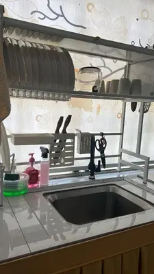 a kitchen counter with a sink and a drying rack at Puterihomestay in Gua Sai