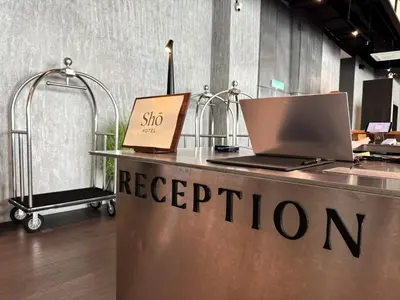 a reception desk with a laptop and a cart at Shō Hotel Penang in George Town