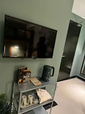 a shelf with cups and a tv on a wall at Very Hotel in George Town