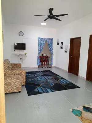 a living room with a couch and a ceiling fan at Dhania Homestay in Gua Sai