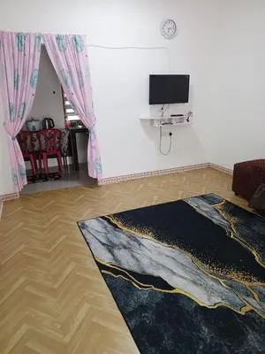 a living room with a television and a rug at Dhania Homestay in Gua Sai