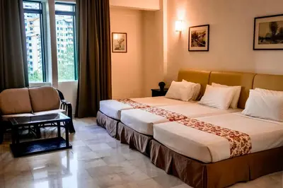 a hotel room with two beds and a chair at Stallions Suite in Jelutong
