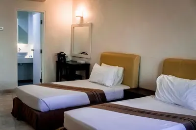a hotel room with two beds and a bathroom at Stallions Suite in Jelutong