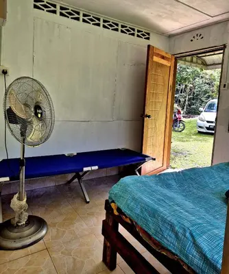 a bedroom with a fan next to a bed at Devalley Basecamp in Kampong Ulu Dong