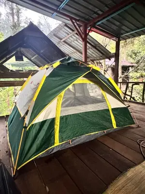 a tent sitting under a roof on a deck at Devalley Basecamp in Kampong Ulu Dong