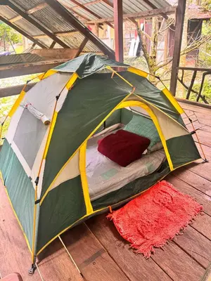 a green and yellow tent sitting on a wooden floor at Devalley Basecamp in Kampong Ulu Dong