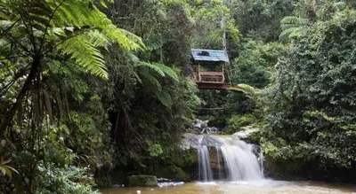 a suspension bridge over a waterfall in the jungle at SPOT ON 89751 Bed Station Guest House in Tanah Rata