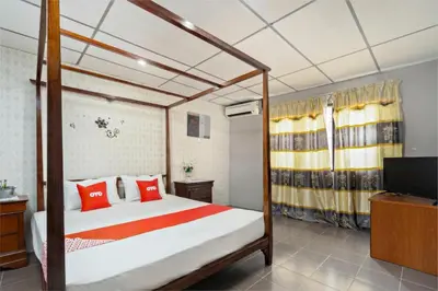 a bedroom with a bed with red pillows and a television at OYO 90929 DJ Hotel in Kampung Damar Laut