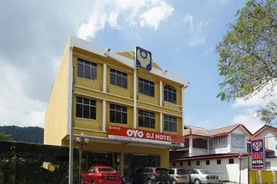 a yellow building with cars parked in front of it at OYO 90929 DJ Hotel in Kampung Damar Laut