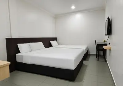 a bedroom with a large white bed and a desk at G Six Hotel in Sitiawan