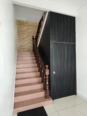 a hallway with a staircase with a black door at G Six Hotel in Sitiawan