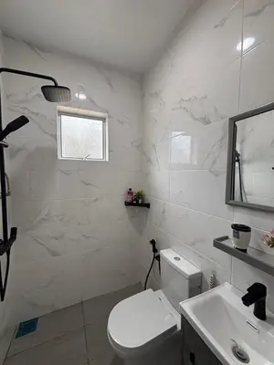 a white bathroom with a toilet and a sink at D'Laman Homestay in Slim River