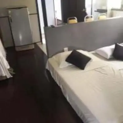 a bedroom with a white bed with a black pillow at Nipah Bay Villa in Pangkor