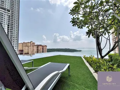 a white chair on a lawn with a view of the water at Urban Suites, 4 Plus 2 Pax, 2 Bedrooms Apartment in Jelutong