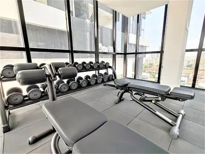 a gym with a bench and weights in a room with windows at Urban Suites, 4 Plus 2 Pax, 2 Bedrooms Apartment in Jelutong