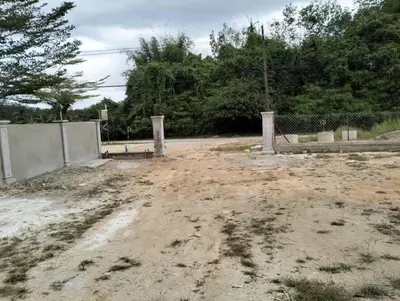 a dirt parking lot with a fence and trees at Mikhail Roomstay in Dabung