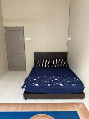 a bed in a room with a blue comforter at Botani Lodge in Ipoh