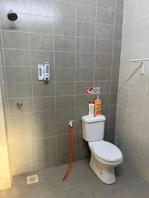 a bathroom with a toilet with an orange hose at Botani Lodge in Ipoh