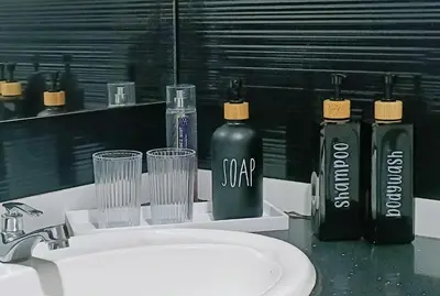 three bottles of soap and glasses on a bathroom sink at Gurney Drive Mansion One by RL SUITE in George Town
