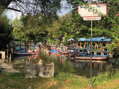 a group of boats are docked in a river at Quadruple Traditional Wooden GuestHouse in Balik Pulau