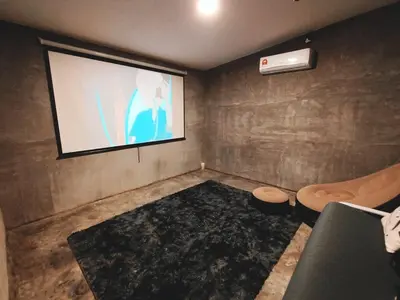 a room with a projection screen with a couch and a chair at Afqa Nest Industrial Charm in Gua Sai