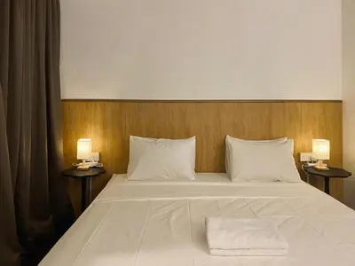 a bedroom with a large bed with two lamps at Chowrasta Suites by Aayu George Town Penang in George Town