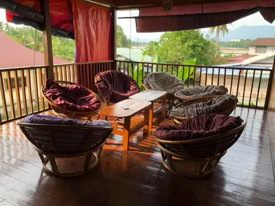 a porch with chairs and a table on a balcony at Junior Suite Nature of Penang Guesthouse in Balik Pulau