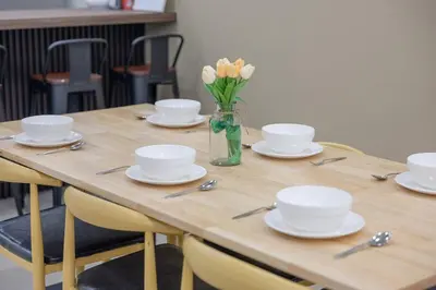 a wooden table with white plates and flowers in a vase at 7 \u53f7 Kota Cozy Homestay 3 storey 22pax-7 Room-SingK in Gua Sai