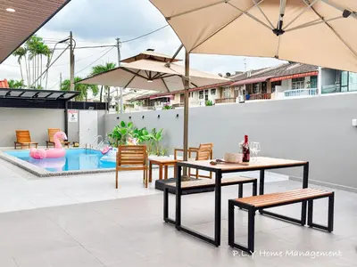 a table and chairs with an umbrella and a pool at HH Villa Private Pool Bercham Ipoh in Ipoh
